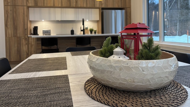 A modern kitchen with wooden cabinets, a white countertop, and a dining area with a large white bowl centerpiece. - OFF-PISTE VBN - LUXURY - MODERN - SPA (St-Raymond)