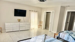 Un dormitorio con dos camas, un televisor, un aparador y una silla.