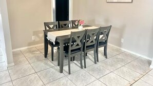 Un comedor con una mesa y sillas, un florero con flores y un cuadro en la pared.