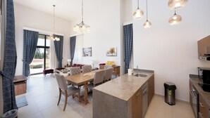 Une cuisine moderne dotée d’un îlot central, un coin repas avec une table et des chaises, et un espace de vie comprenant un canapé et une table basse.