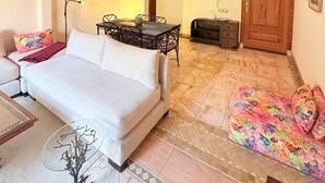 A spacious living area with a sofa, a dining table, and a fireplace. - 2-bed Apartment with Garden & shared Pool- Moroccan - Modern Style (Marrakech)