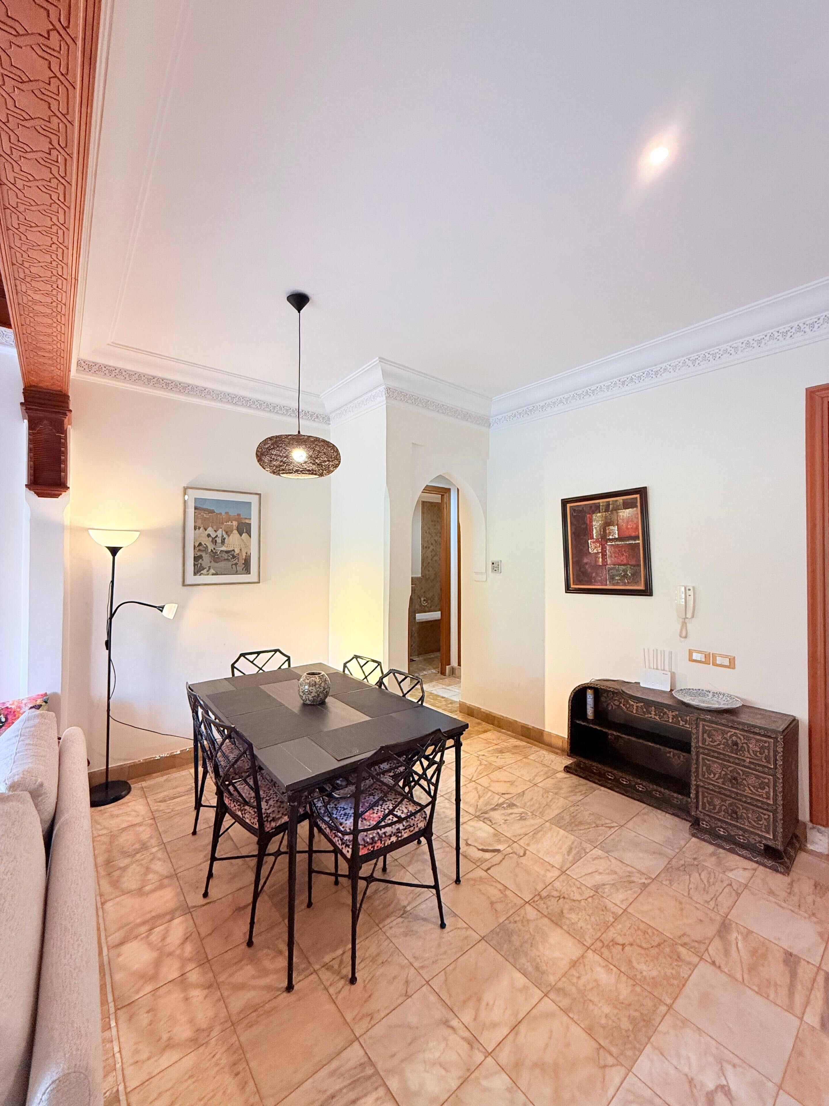 A dining area with a table and chairs, a floor lamp, and a decorative console table with a plate.