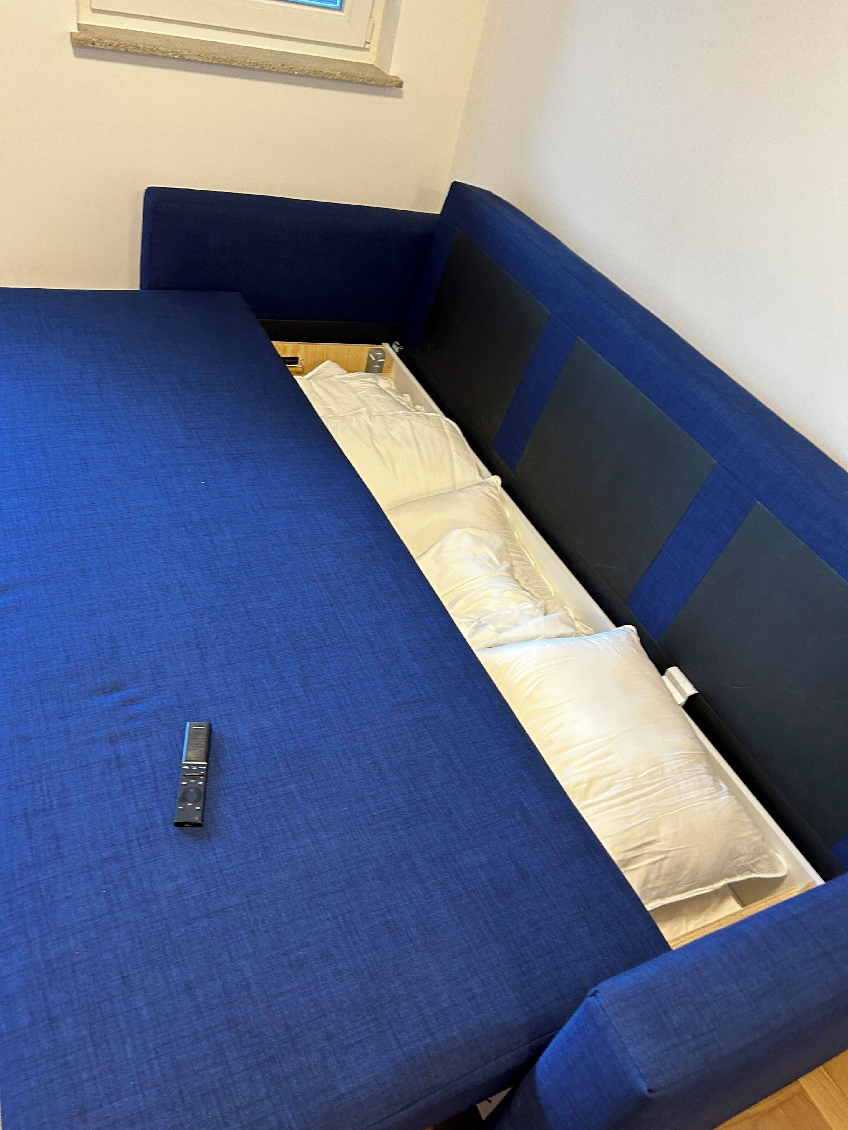 A blue sofa bed with a remote control on it.