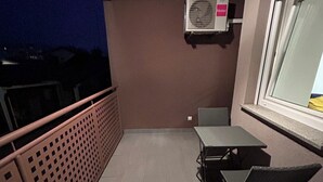 A balcony with a table and chairs, a window, and an air conditioning unit. - Apartment Fran (Zagreb)