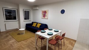 A dining area with a table and chairs, a sofa, a radiator, and a clock on the wall. - Apartment Fran (Zagreb)