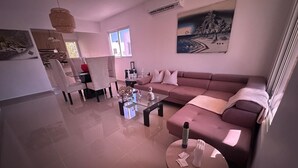 A modern living room with a sofa, a coffee table, and a dining area with chairs. - 3-bedroom house in delightful Punta Cana with AC (Punta Cana)
