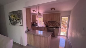 A modern kitchen with a central island, wooden cabinets, and a large window. - 3-bedroom house in delightful Punta Cana with AC (Punta Cana)