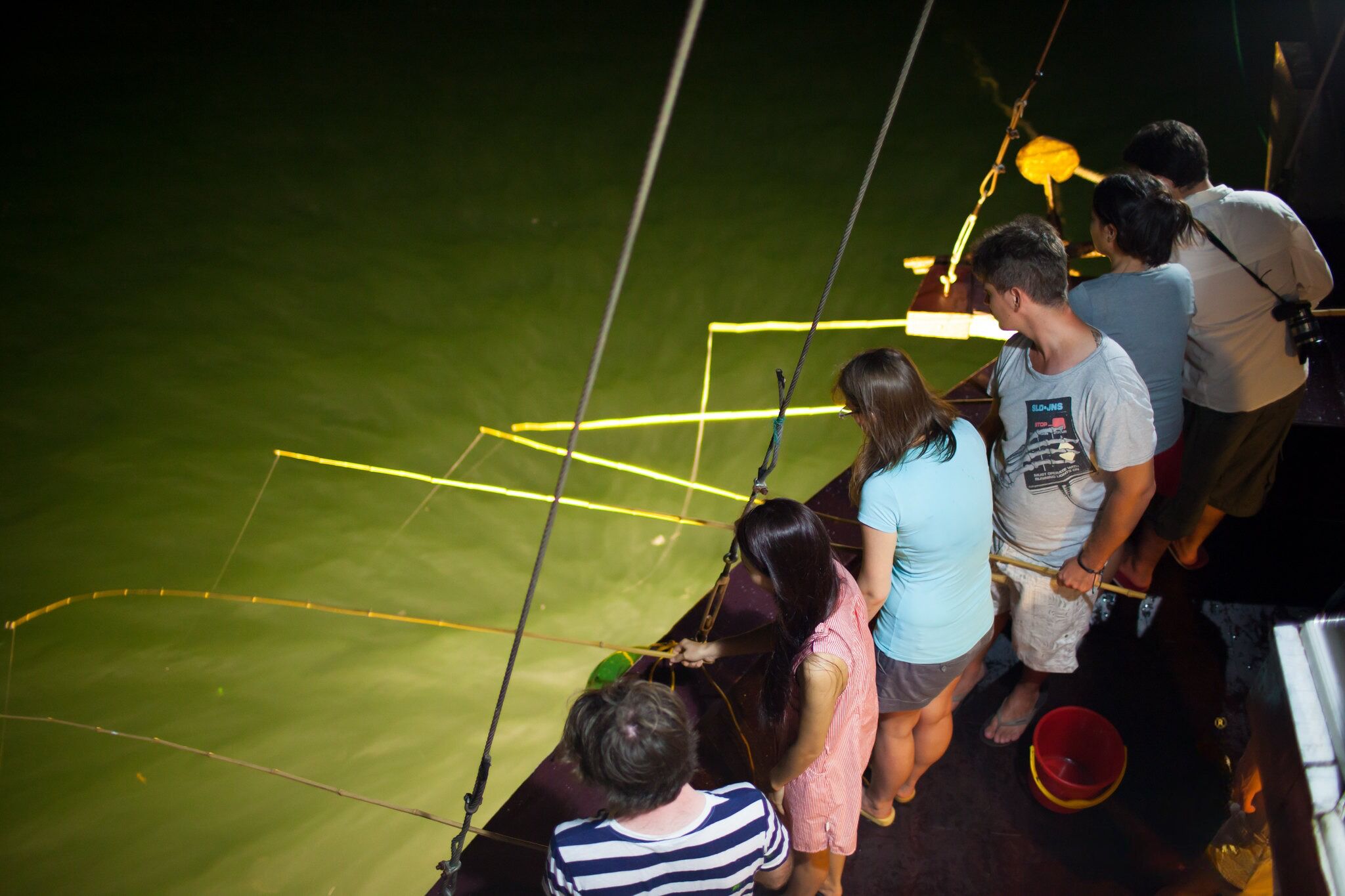 A group of people on a boat with a green deck and yellow lines.