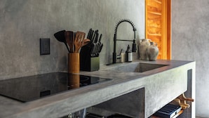 Een keuken met een modern ontwerp, met een inbouwfornuis, een spoelbak en een houten keukengerei houder.