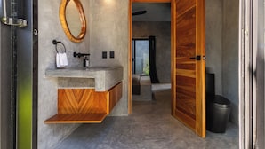 Een moderne badkamer met een betonnen wastafel, een houten wastafelmeubel en een grote spiegel.