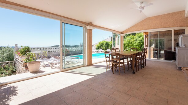 A spacious patio with a dining area, large sliding glass doors, and a view of a swimming pool. - House with swimming pool and beautiful view (Lédenon)