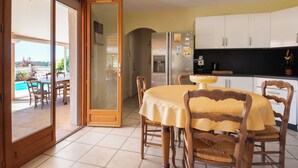 A dining area with a table and chairs, a refrigerator, and cabinets. - House with swimming pool and beautiful view (Lédenon)