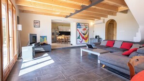 A spacious living area with a grey sofa, wooden ceiling beams, and a tiled floor. - House with swimming pool and beautiful view (Lédenon)