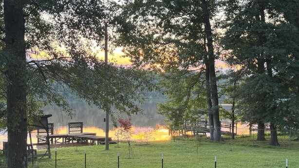 A grassy area with a wooden deck and picnic tables, surrounded by trees and a fence. - High falls Lakefront Dock, Dock, Lake Views & Game Room (Jackson)