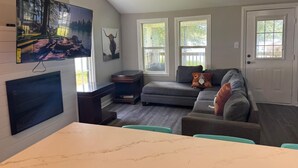 A living room with a fireplace, a television mounted on the wall, a couch, and a dining table. - High falls Lakefront Dock, Dock, Lake Views & Game Room (Jackson)