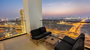 A balcony with a city view, a sofa, a small table, and a chair. - Private Pool | Movies in bed | No Camels (دبي)