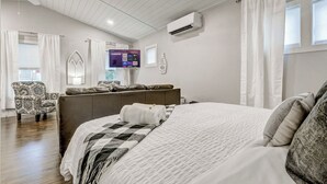 Ein modernes Schlafzimmer mit einem großen Bett, einer Couch, einem Fernseher und einer Klimaanlage.