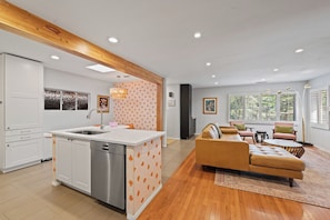 A modern kitchen with white cabinets, a stainless steel dishwasher, and a patterned backsplash.