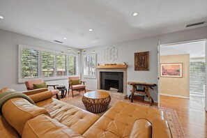 A living room with a leather sofa, a round coffee table, and a fireplace.