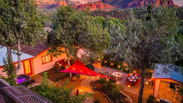 A well-lit outdoor patio area with a fire pit, seating, and a red canopy.