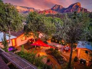 A well-lit outdoor patio area with a fire pit, seating, and a red canopy. - Zen Garden Retreat with Hiking Access, private fenced backyard (Sedona)