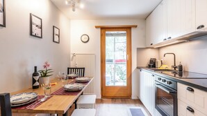 A compact kitchen with a dining area, wooden cabinets, a built-in oven, and a window with a view. - Forest- finest selections (Zermatt)