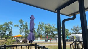A covered outdoor area with a pool, umbrellas, and a fenced playground.