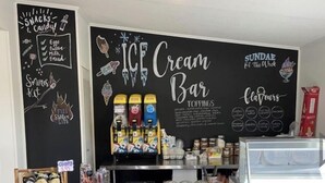 A snack bar with ice cream and sundae options, a chalkboard menu, and various snacks and candies.