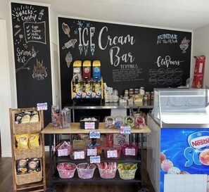 A snack bar with ice cream and sundae options, a chalkboard menu, and various snacks and candies.