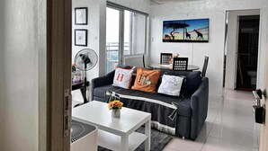 Un salon moderne avec un canapé gris, une table basse blanche et un tableau représentant des girafes accroché au mur.