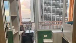 Une chambre compacte avec vue sur les immeubles de grande hauteur, un petit coin salon et une armoire intégrée.