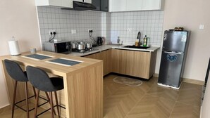 Una cocina moderna con una isla de madera, taburetes de bar, un refrigerador de acero inoxidable y un piso con patrón de espiga.