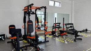 Un gimnasio con equipo de levantamiento de pesas, bancos y un espejo.