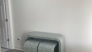 Une pièce avec un plancher en bois, un banc à motifs, une horloge murale et une porte.