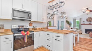 A modern kitchen with white cabinets, stainless steel appliances, and a wooden countertop. - Riverside Cottage just a short walk to downtown! (Bonita Springs)