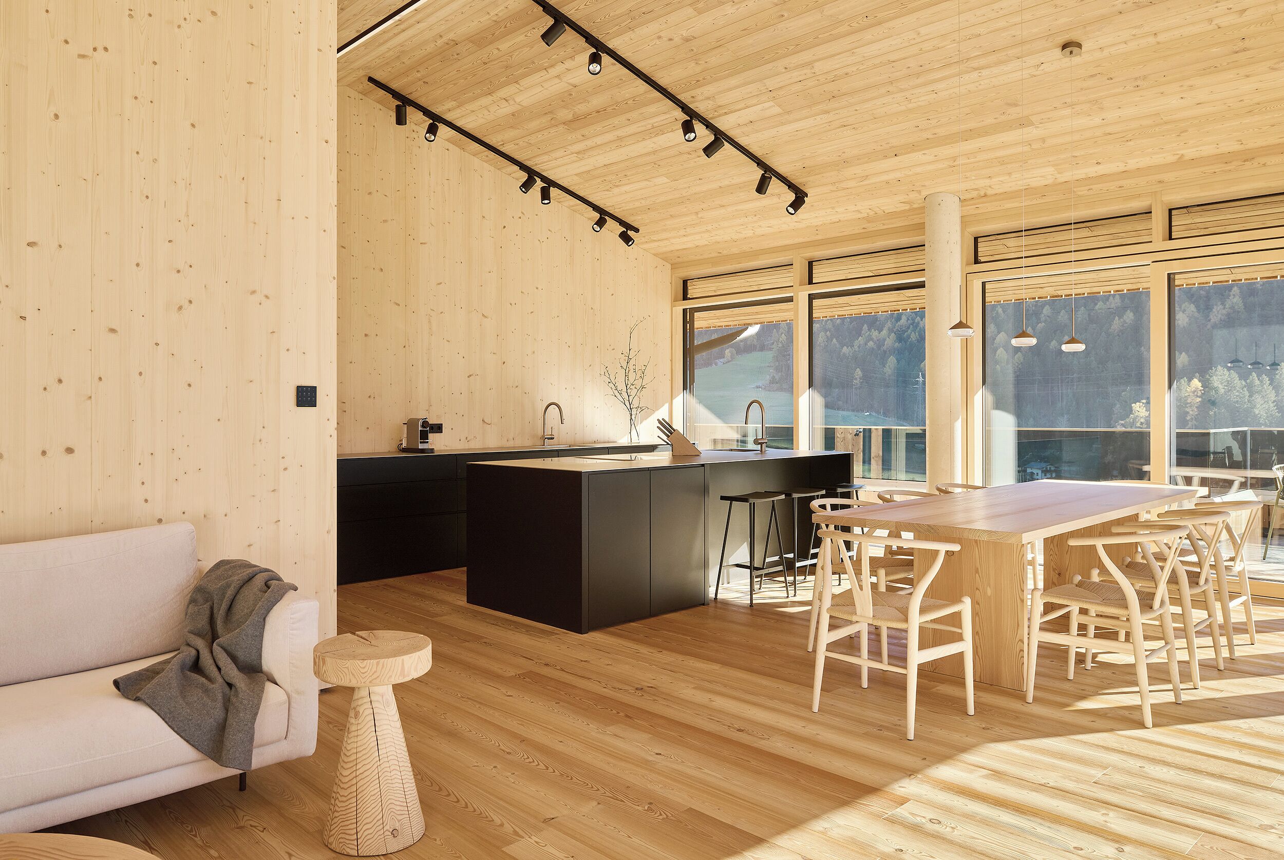 A modern kitchen with a wooden island, bar stools, and a dining table.