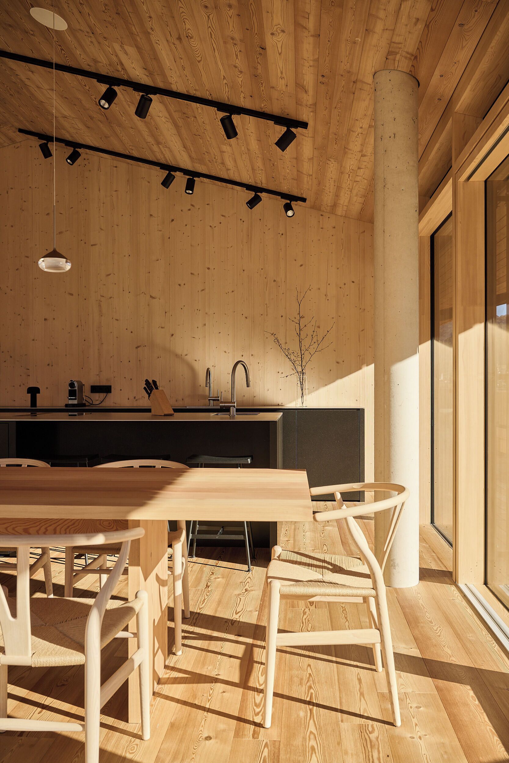 A modern kitchen with wooden cabinetry, a central island, and a dining area with a wooden table and chairs.