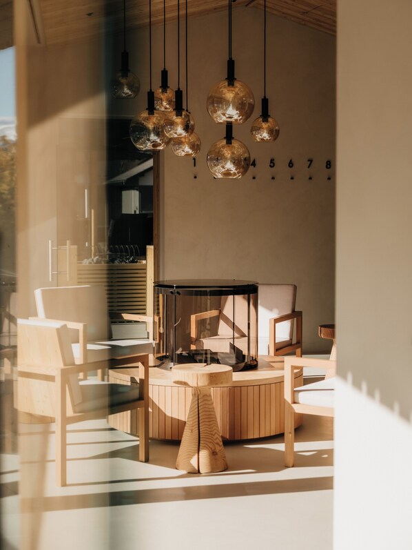 A modern interior with a wooden dining area, hanging spherical light fixtures, and a glass partition.