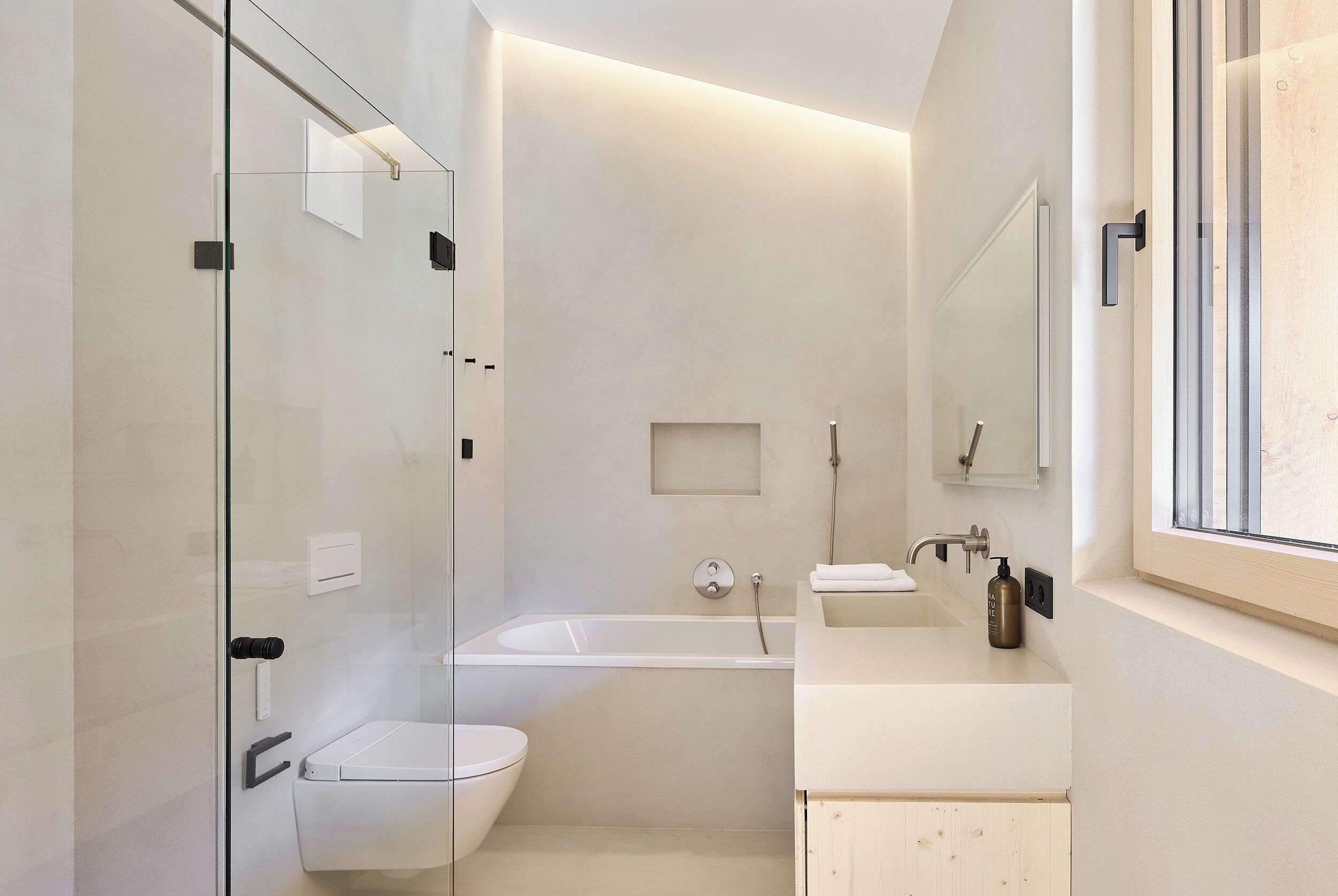 Ein modernes Badezimmer mit Duschkabine aus Glas, einer Badewanne, einer Toilette und einem Waschbecken mit Spiegel.