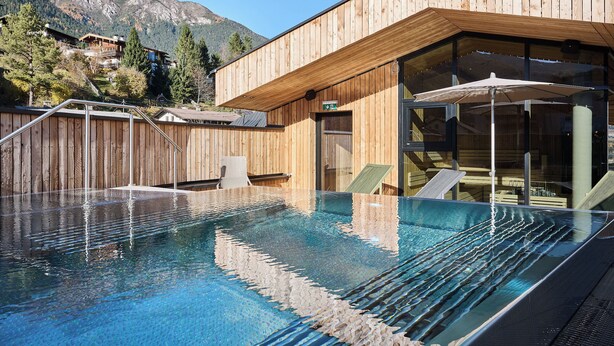 A wooden building with a glass pool and outdoor seating. - Lärchenlodge SkySpa und Rooftop Pool (Fulpmes)