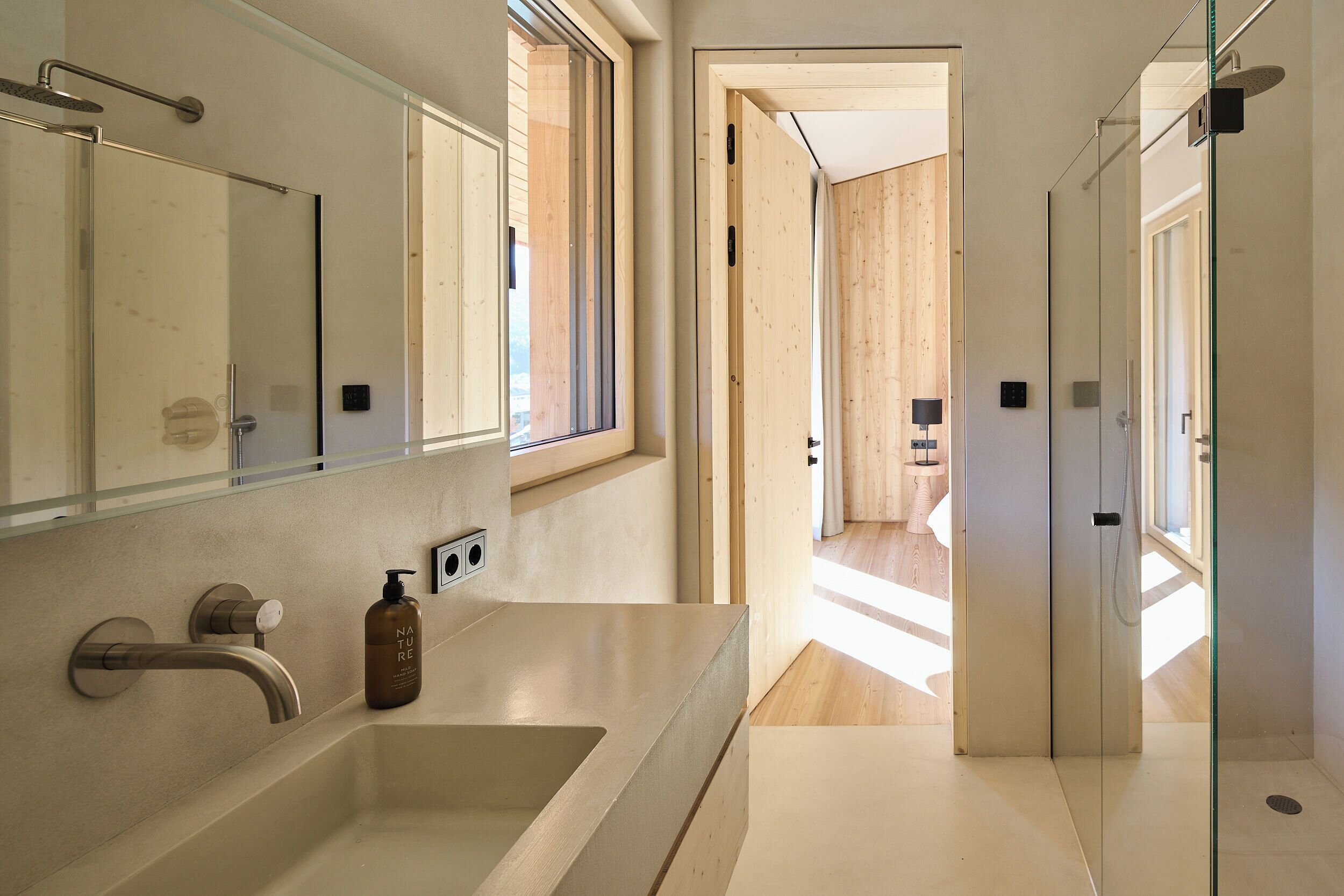 Une salle de bain moderne avec un grand miroir, un lavabo et une douche.