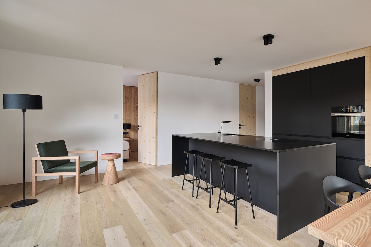 A modern kitchen with a central island, bar stools, and a dining area with a table and chairs.