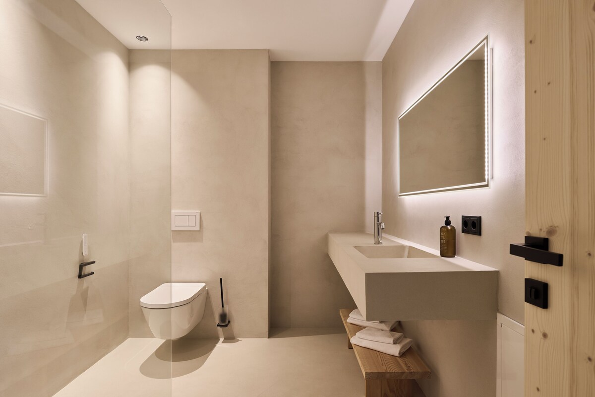 A modern bathroom with a toilet, sink, and mirror.