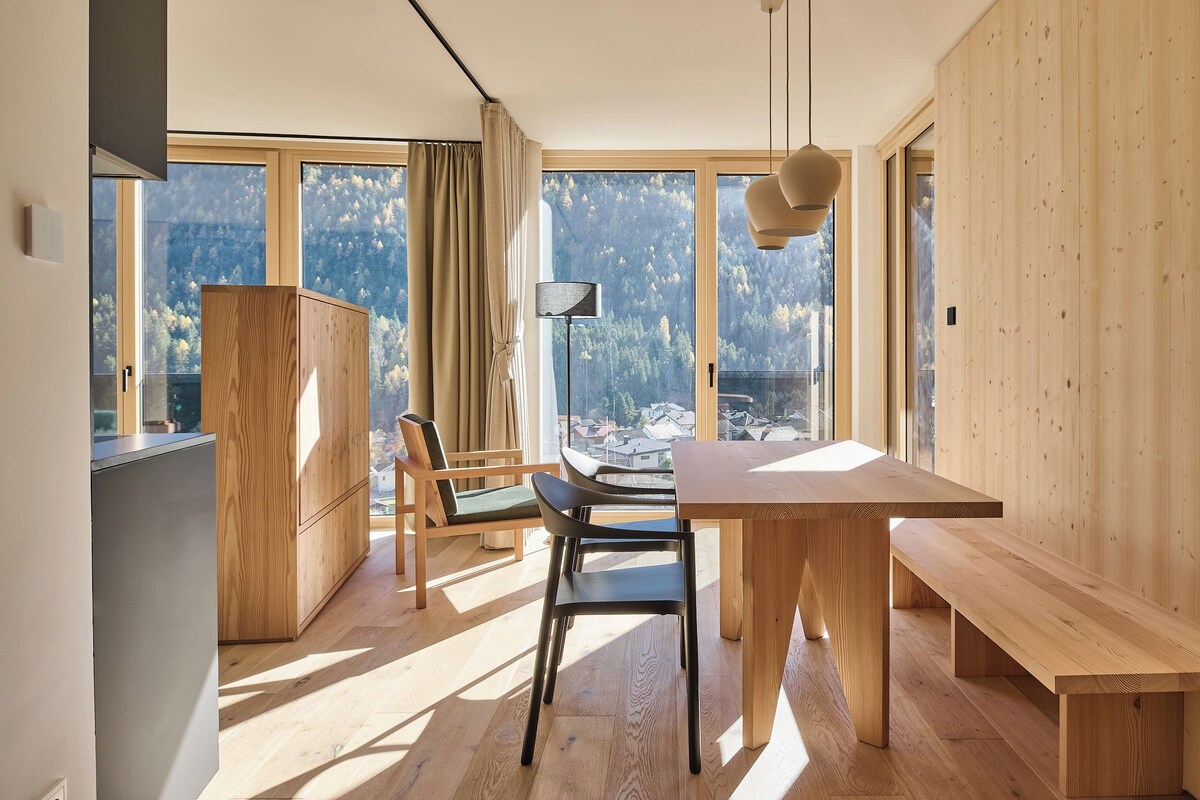 Une cuisine moderne avec des meubles en bois et une grande fenêtre donnant sur un paysage montagneux.