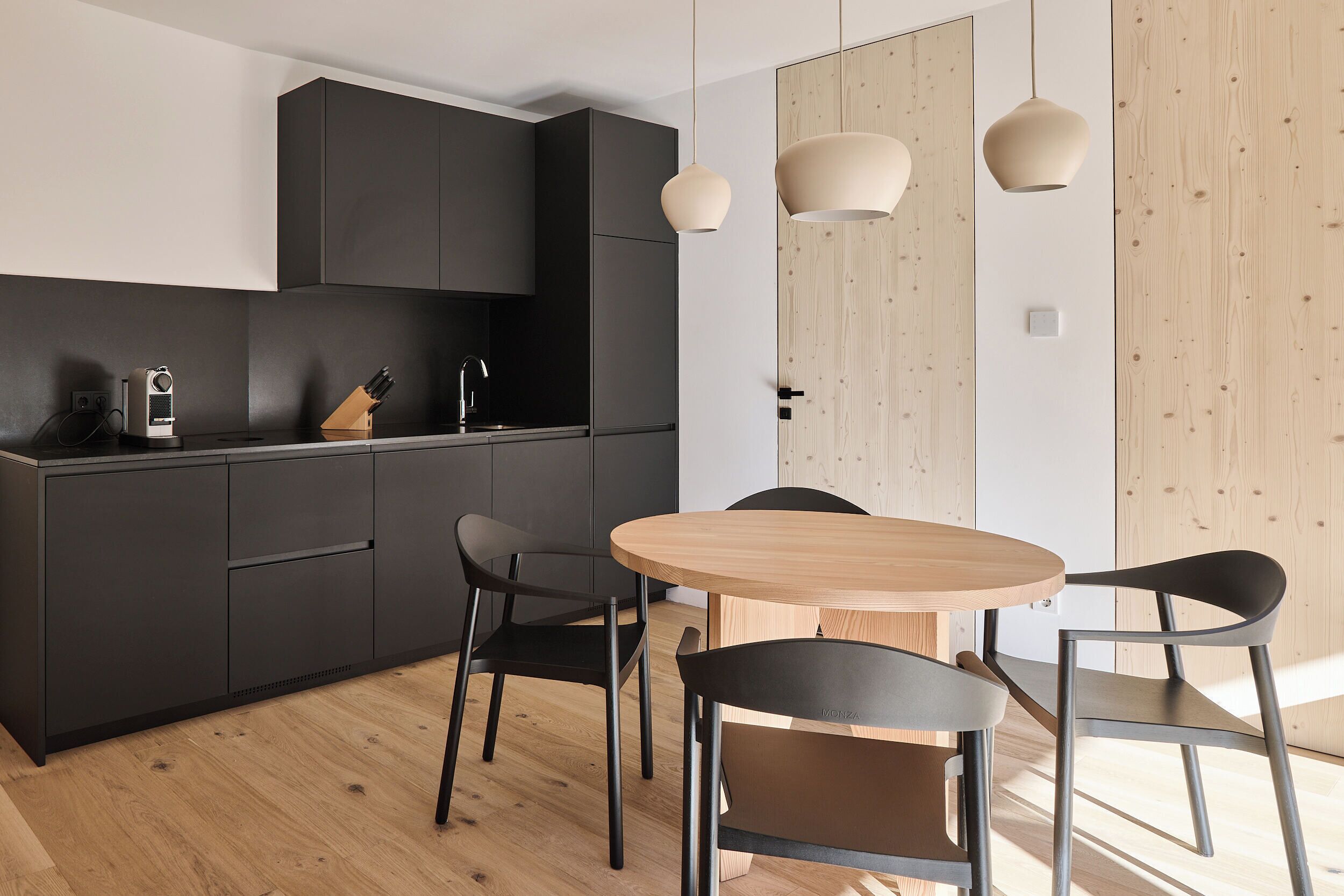 Una cocina moderna con armarios oscuros, una mesa de comedor de madera y sillas negras.