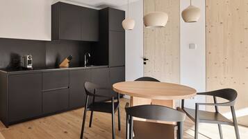 Una cocina moderna con armarios oscuros, una mesa de comedor de madera y sillas negras.