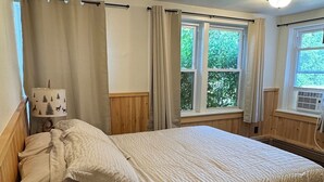 Une chambre à coucher avec un lit, des rideaux, une fenêtre et un luminaire au plafond.