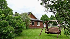 Une cabane en bois avec une balançoire dans une cour verdoyante.