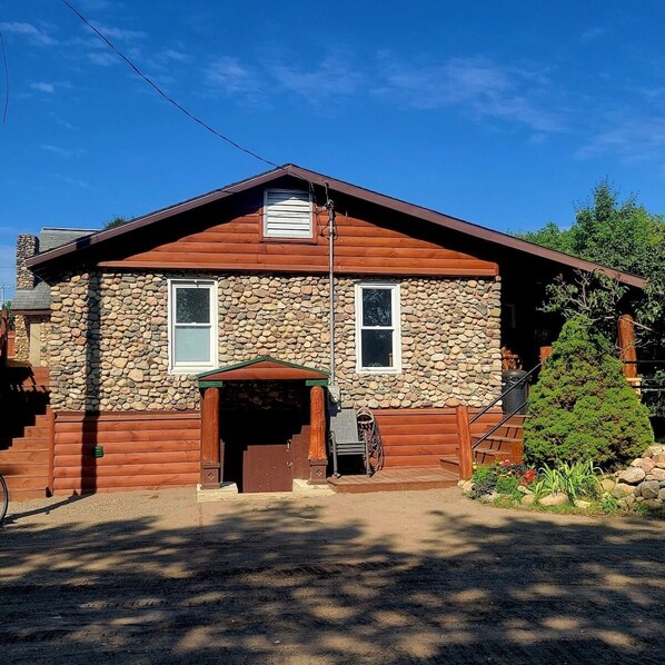 A two-story log cabin with a stone exterior, a front porch, and a small attached garage. - Historical Stone and Log Cabin (Paris)