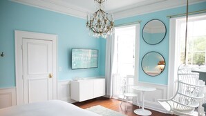 A bedroom with a bed, a white dresser, a chandelier, two round mirrors, and a window with a view. - Bosch Huis Rosé • Central • VIP • Parking (Savannah)